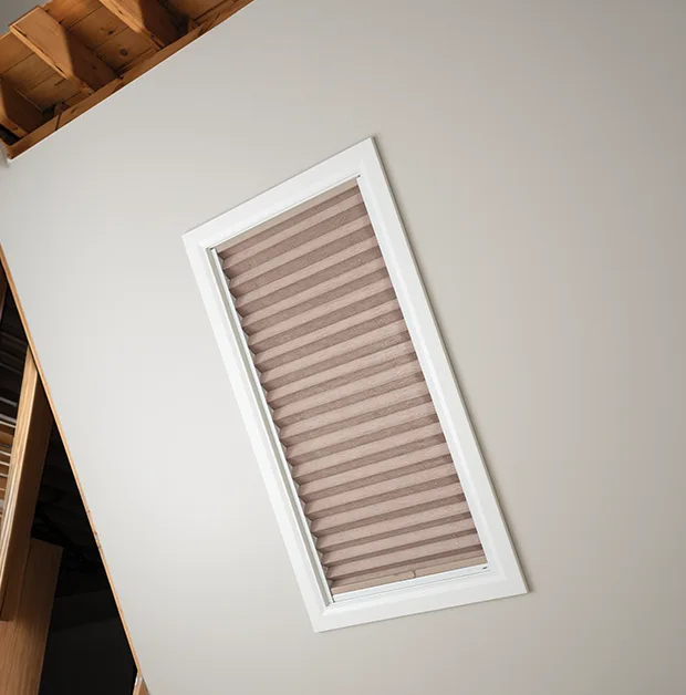 Tan pleated shades on a skylight on a white ceiling