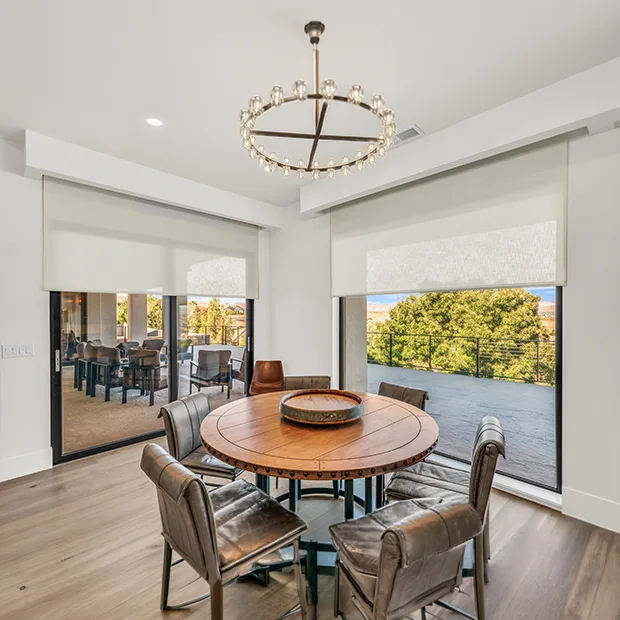 White roller shades on a sliding glass door and large window in a modern dining room