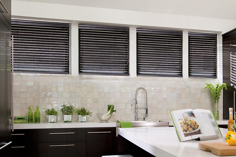 Special shaped faux wood blinds in several windows above a sink.
