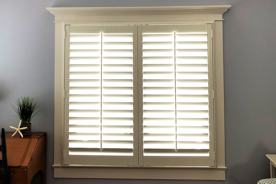 Dormer window with white Polywood shutters. Inside an attic room.