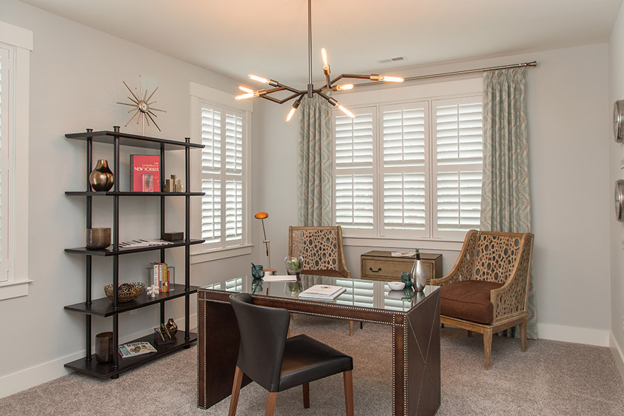 Colorful curtains can add a bit of flair with white Polywood shutters in St. George. Sage green patterned curtains on white polywood shutters in an office.