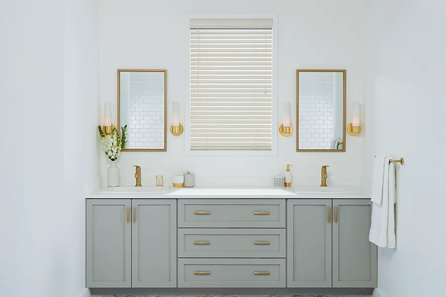 White faux-wood window blind in a white bathroom with a grey double vanity