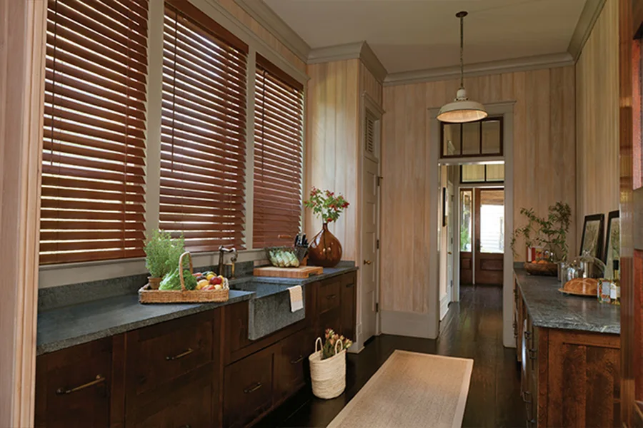Chestnut faux-wood blinds on windows behind a kitchen sink